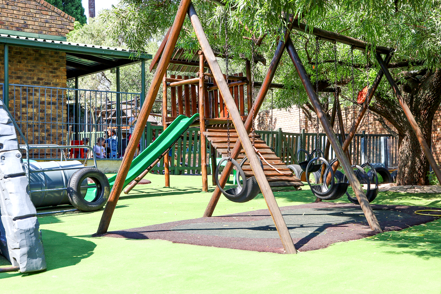 A playground with a slide , swings , and tire swings.