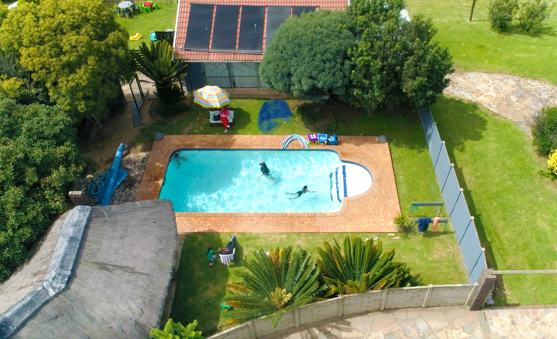 An aerial view of a swimming pool with a house in the background