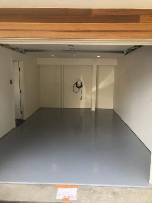 An empty garage with a gray floor and white walls.