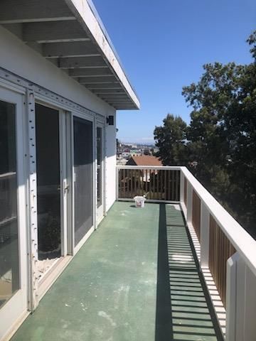 A balcony with a view of a city and trees on a sunny day.