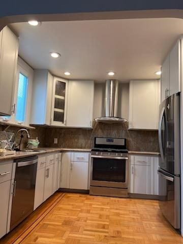 A kitchen with white cabinets , stainless steel appliances , and hardwood floors.
