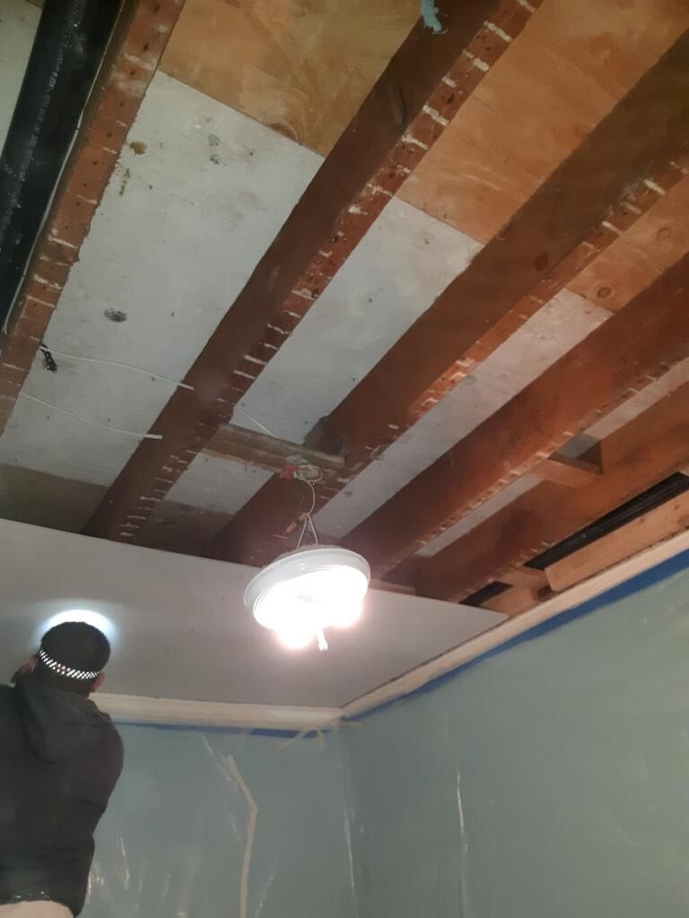 A ceiling with wooden beams and a light hanging from it.