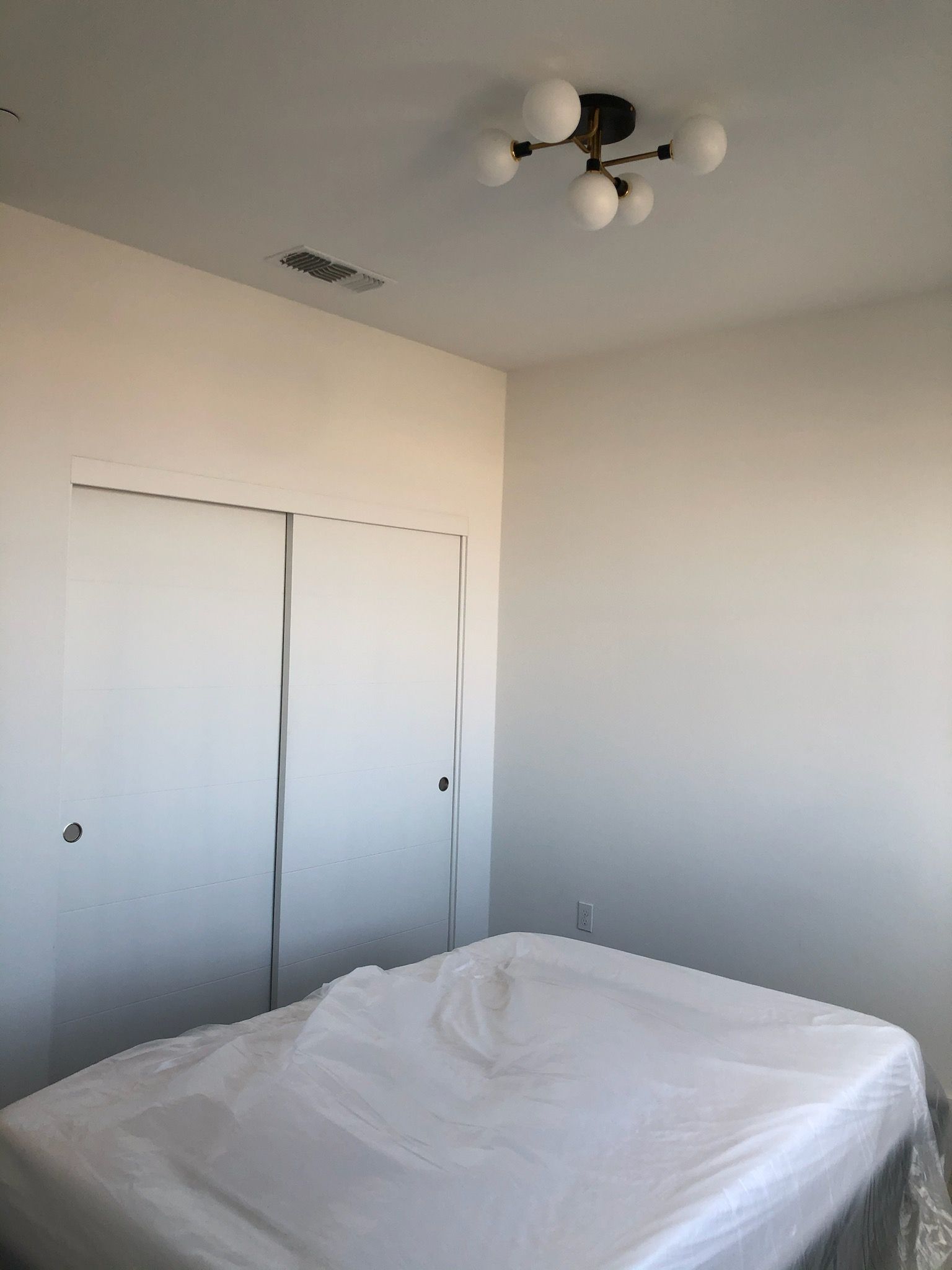 A bedroom with a bed and a chandelier hanging from the ceiling.