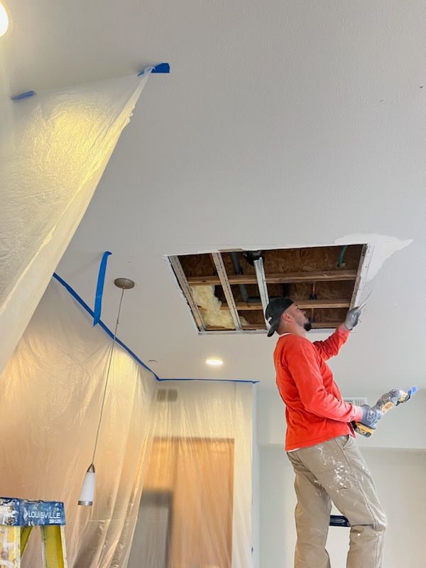 A man is painting the ceiling of a room.