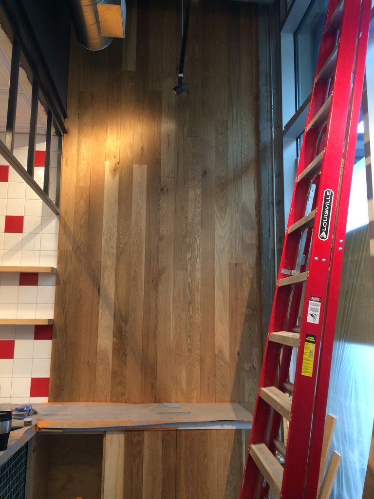 A red ladder in a room with a wooden wall