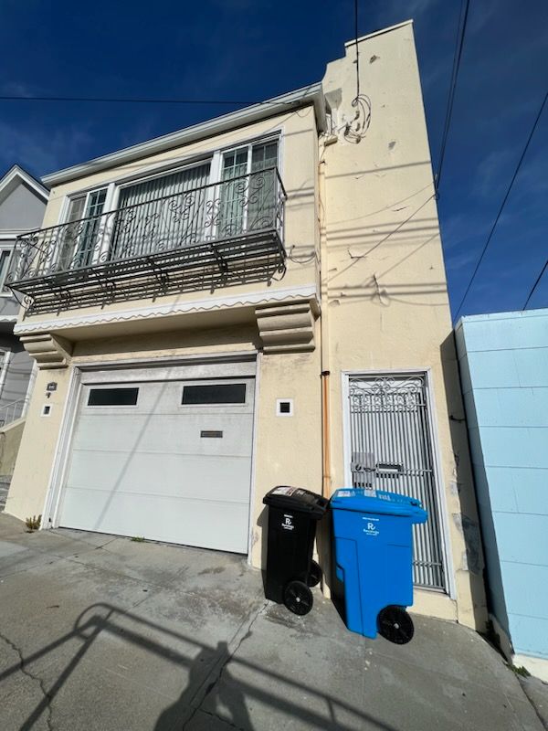 Two trash cans are parked in front of a building