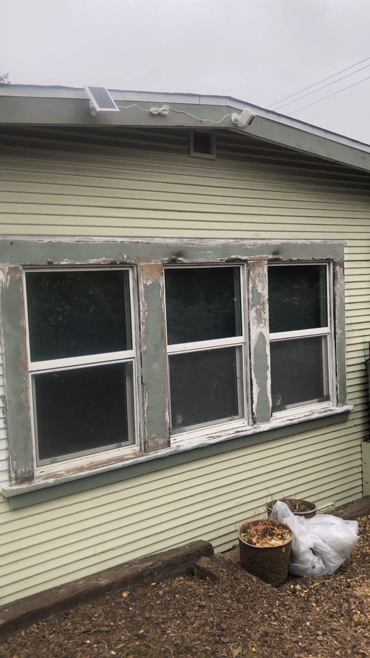 A house with a lot of windows and a bucket of wood in front of it.
