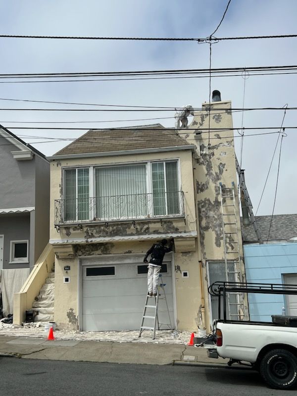 A white truck is parked in front of a house that is being painted.