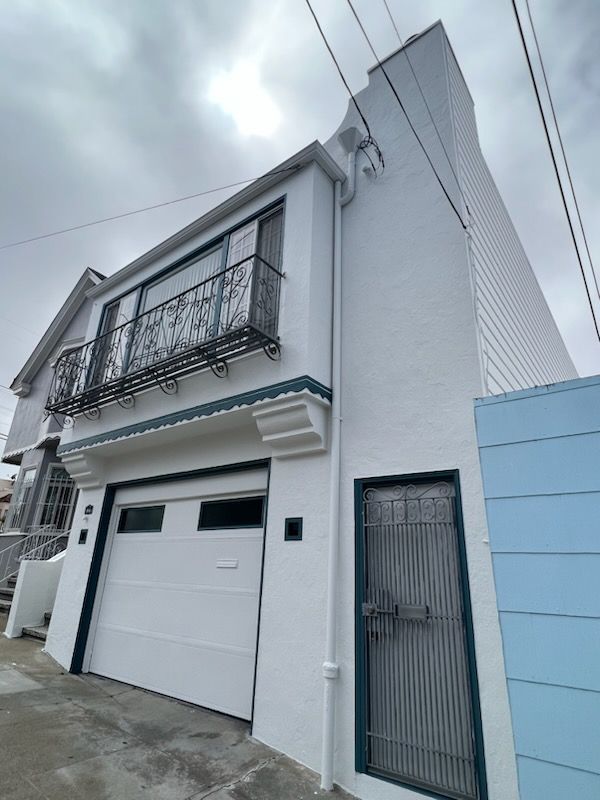 A white house with a garage door and a balcony
