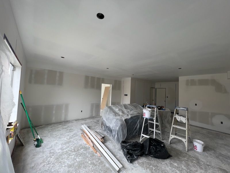 A room with a couch and a ladder in it is being remodeled.