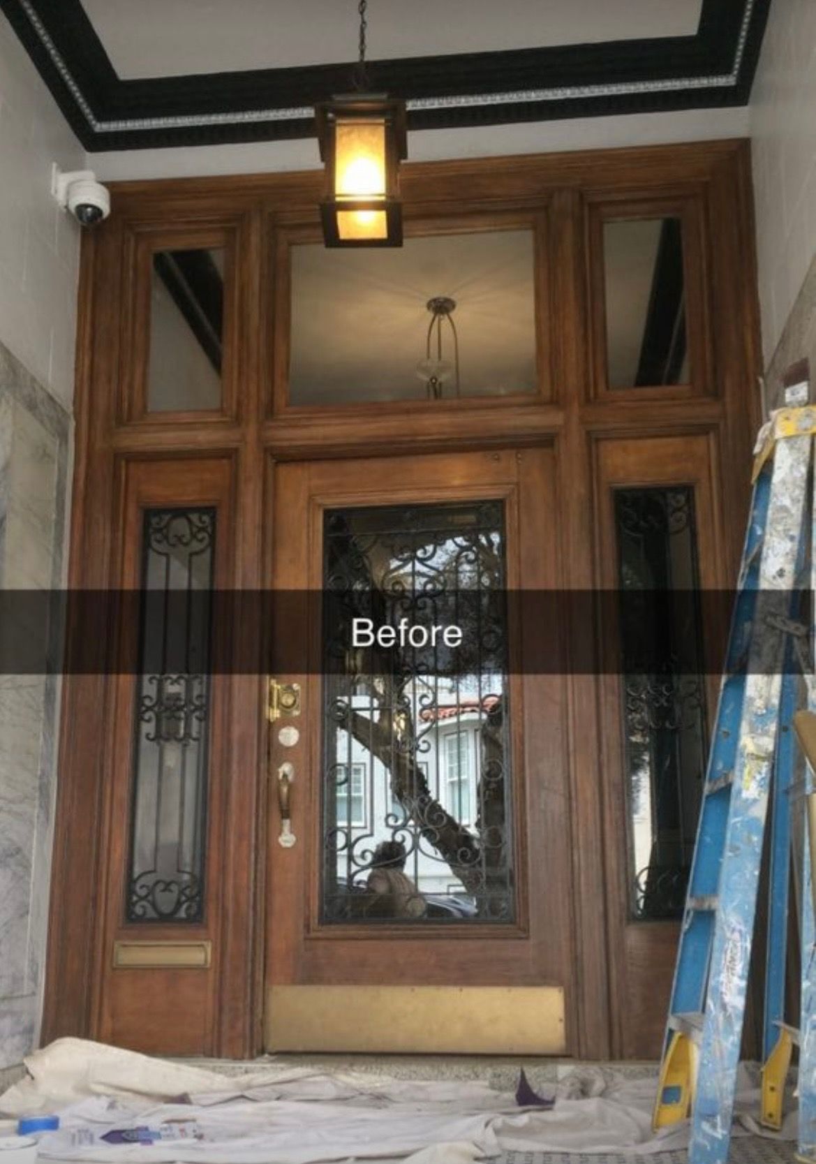 A before picture of a wooden door with a ladder in front of it.