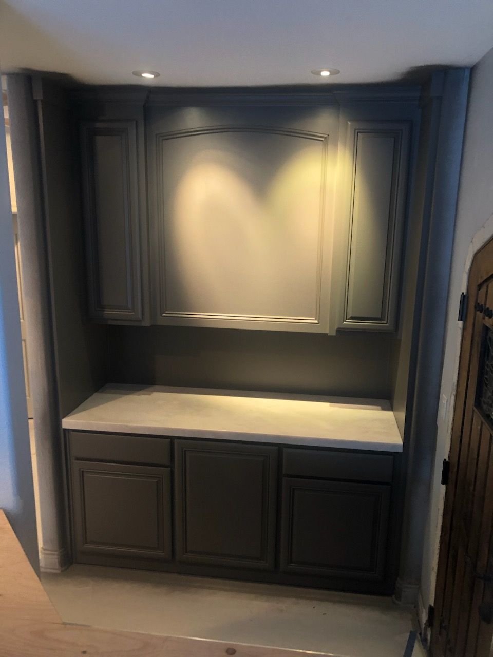 A kitchen with gray cabinets and a white counter top.