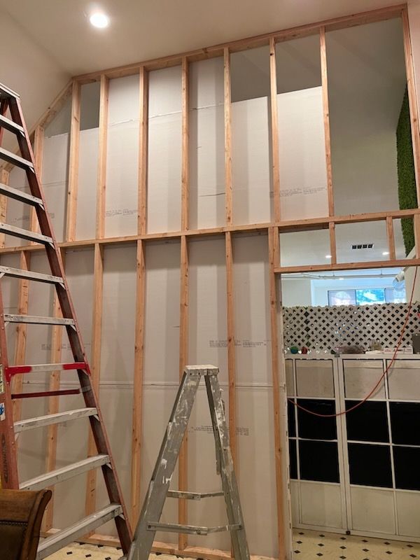 A ladder is sitting in front of a wall that is being built.