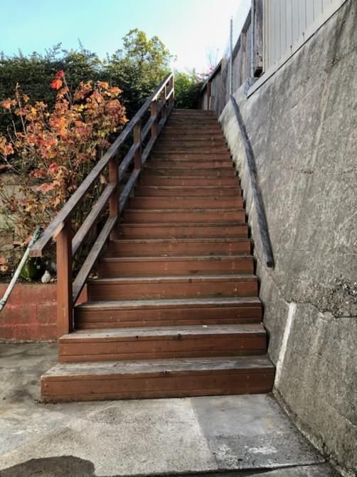 A set of wooden stairs with a railing going up a hill.