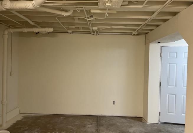 An empty basement with white walls and a white door.