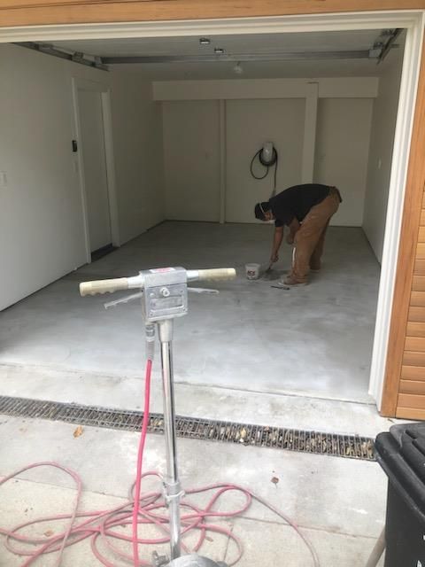 A man is working on the floor of a garage.