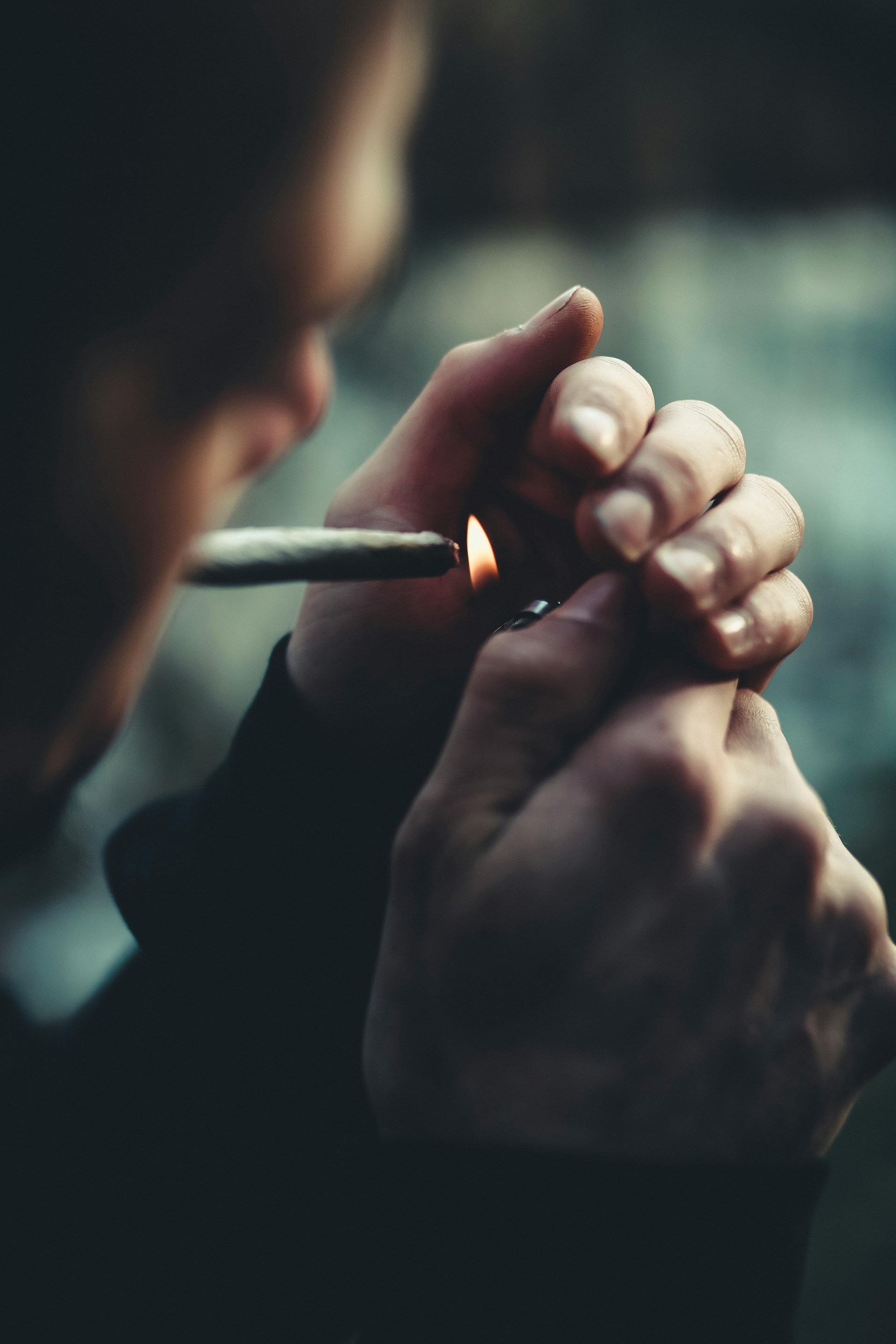 Man lighting a cigar with a lighter, close-up of hands and face.