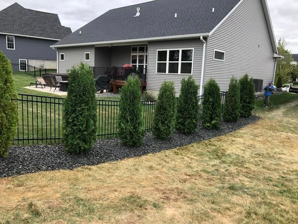 A house with a fence and trees in front of it.