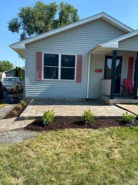 A white house with pink shutters and a walkway in front of it.