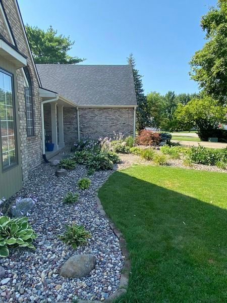 A house with a lush green lawn and rocks in front of it.