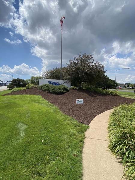 A walkway leading to a building with a flag pole in the background.