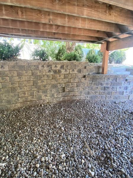 There is a brick wall under a wooden deck.