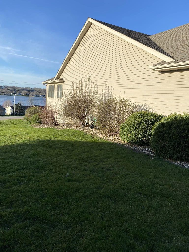 A house with a large lawn in front of it and a lake in the background.