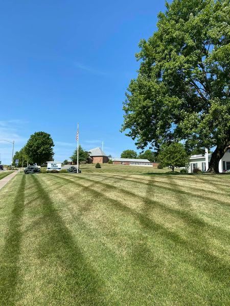 A lush green lawn is being mowed on a sunny day.