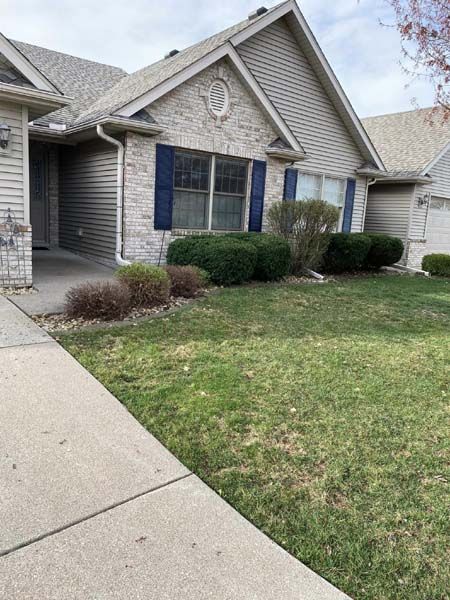 A house with a large lawn and a sidewalk in front of it.