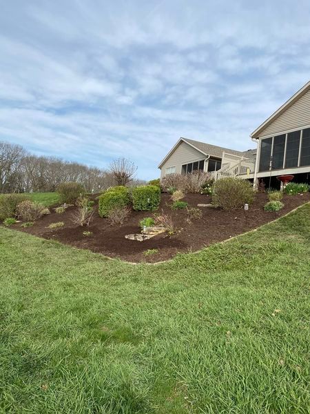 A house with a screened in porch and a large lawn in front of it.