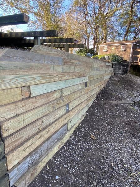 A wooden fence is being built in a yard with trees in the background.