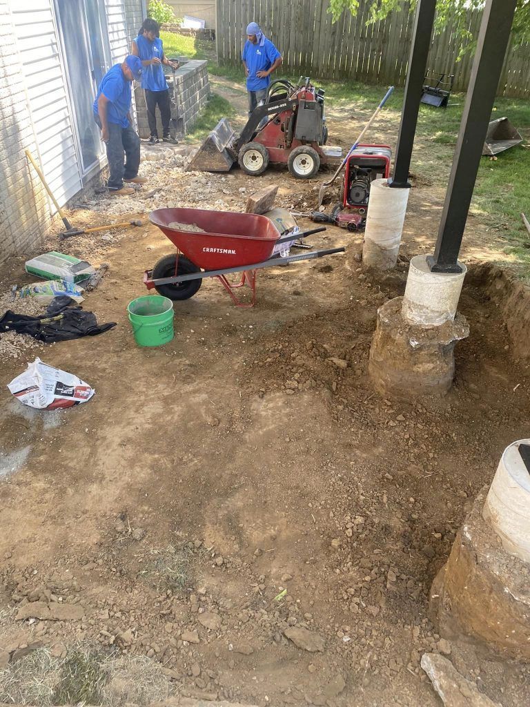 A wheelbarrow is sitting in the dirt next to a tractor.