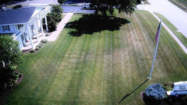 An aerial view of a lush green lawn with a flag in the foreground.