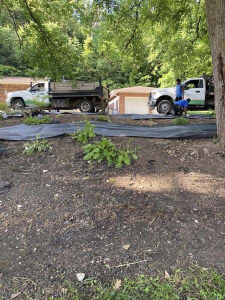 A dump truck is parked in the dirt in front of a house.