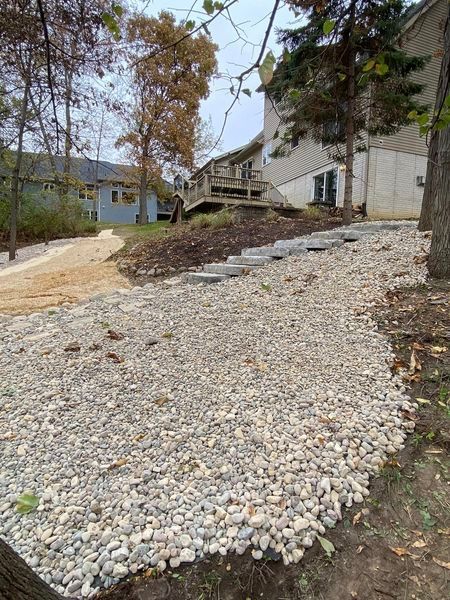 A gravel path leading to a house with a deck in the background.