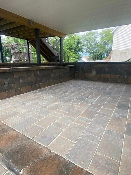 A patio with a brick wall and a staircase in the background.