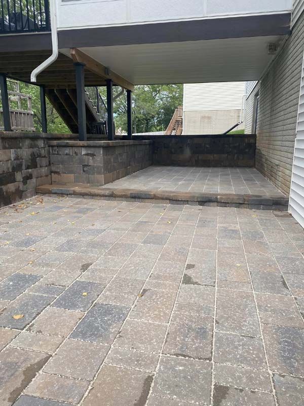 A patio with a deck and stairs underneath it.