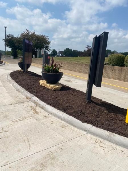 A concrete curb with planters and a sign on it