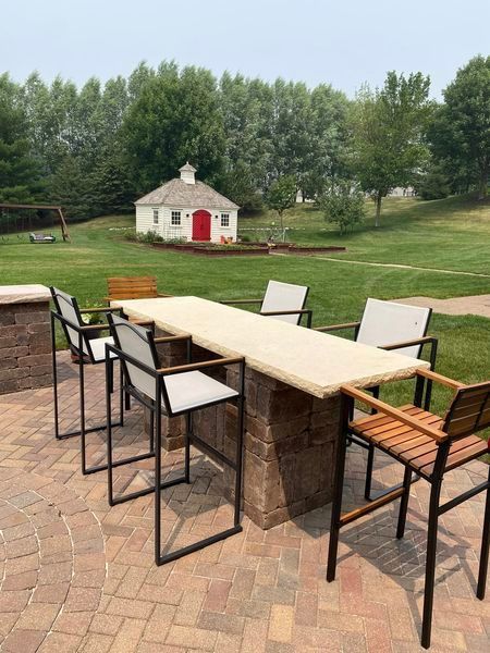 A patio with a table and chairs and a red barn in the background.