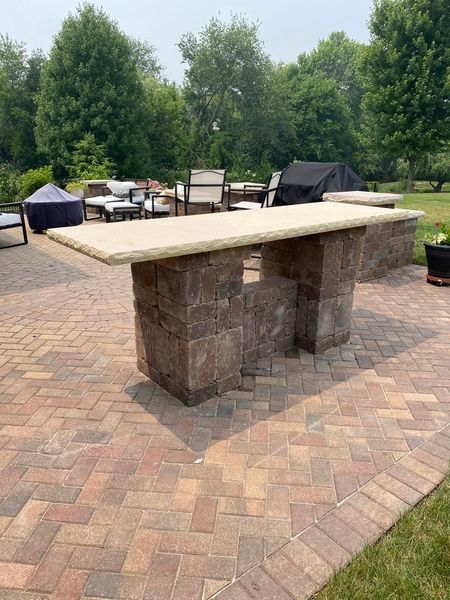 A stone table is sitting on top of a brick patio.