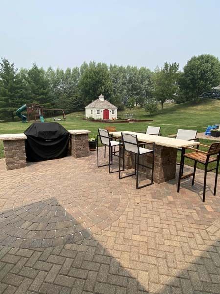 A patio with a table and chairs and a grill.