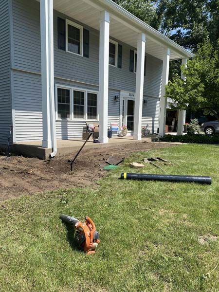 A lawn blower is sitting on the grass in front of a house.