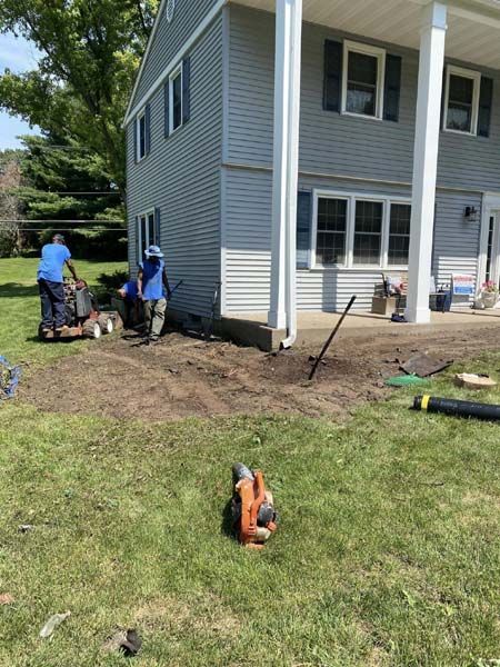 A group of people are working in front of a house.
