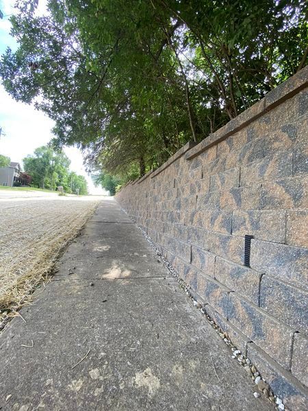A brick wall along a sidewalk next to a road.
