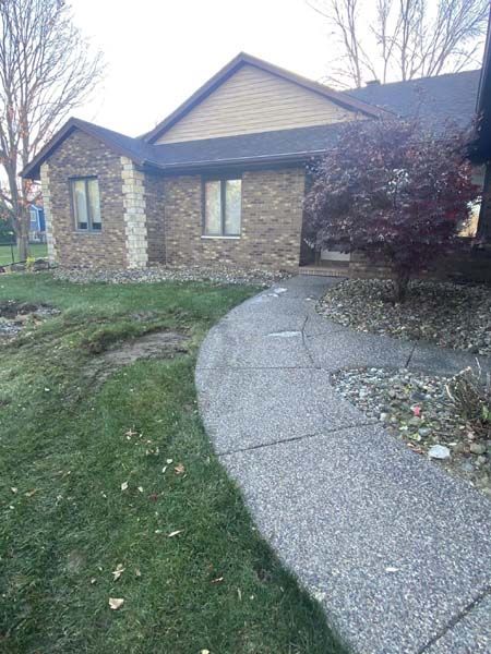 A brick house with a concrete walkway leading to it.