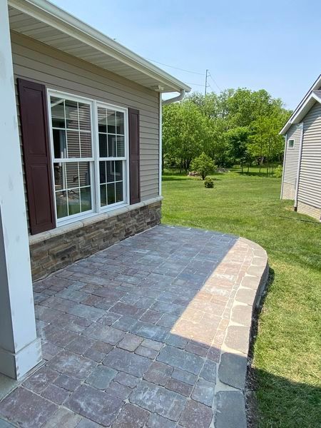 There is a patio in front of a house with a large window.