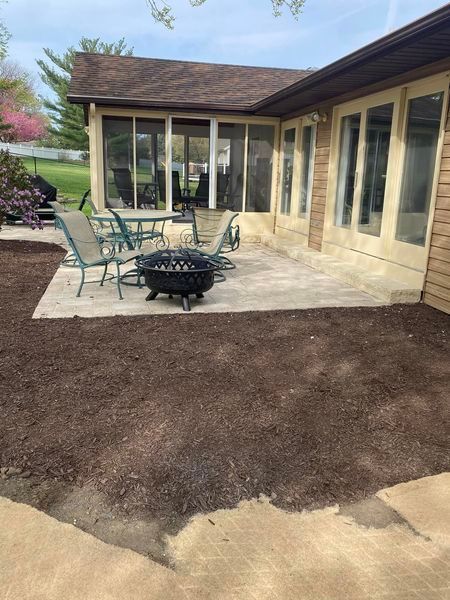 A patio with a fire pit and tables and chairs in front of a house