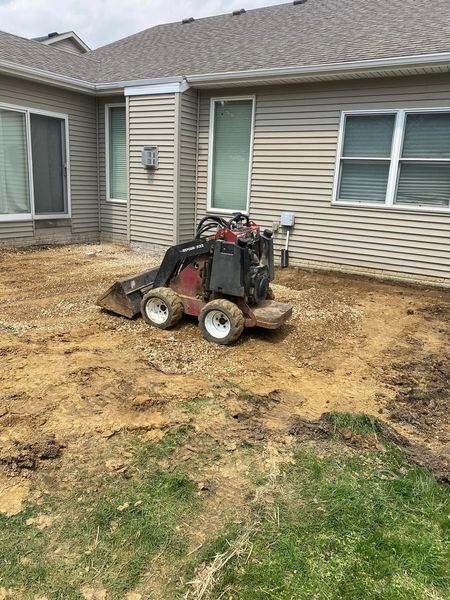 A small bulldozer is sitting in the dirt in front of a house.