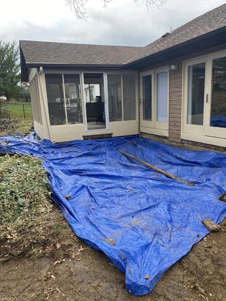 A blue tarp is covering a patio in front of a house.
