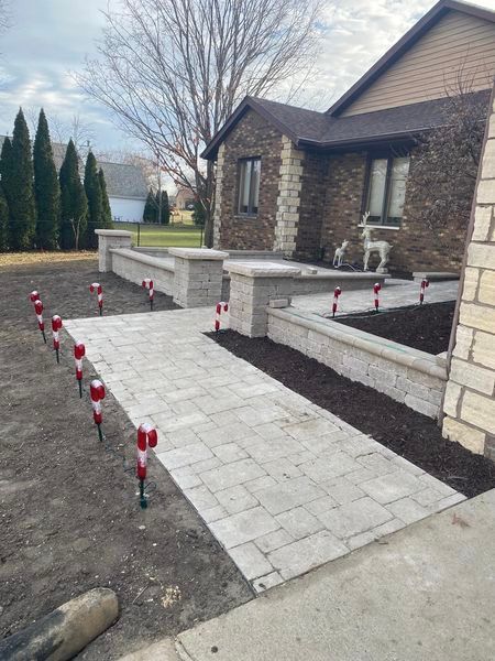 A stone walkway leading to a house with a brick wall.